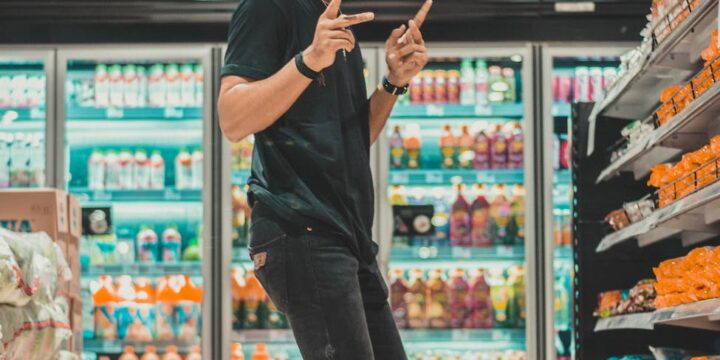 young man in mask dancing near supermarket shelf